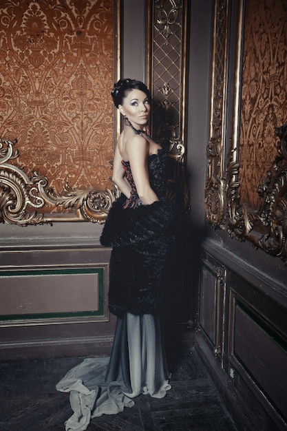 Молодая красивая женщина, стоя в комнате дворца