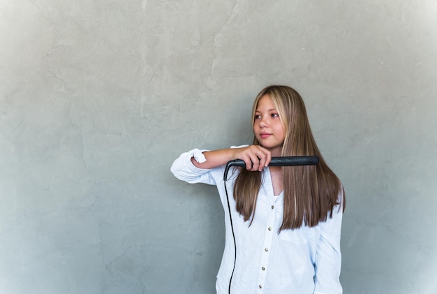 Young beautiful woman straightening her long hair