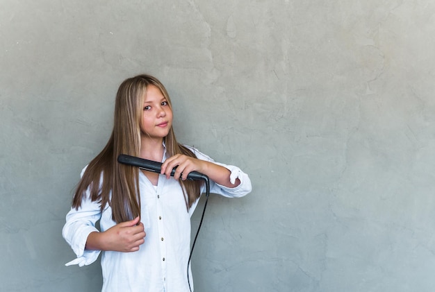 Giovane bella donna che raddrizza i suoi capelli lunghi