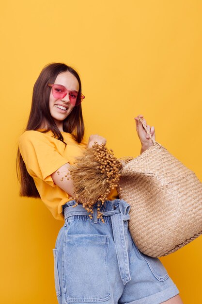 Young beautiful woman straw bag emotions summer style yellow background