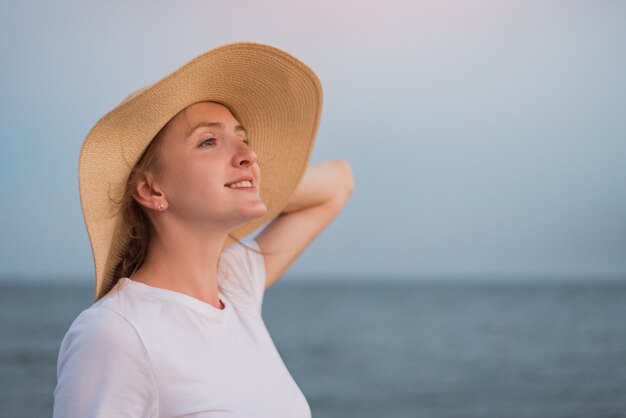 海背景に麦わら帽子の若い美しい女性。航海休暇