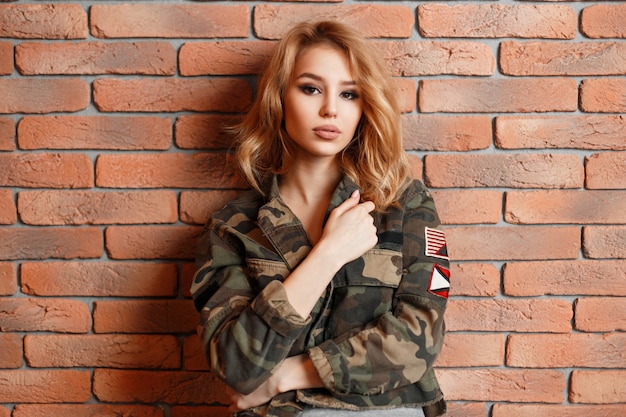 Молодая красивая женщина в стильной модной куртке возле кирпичной стены