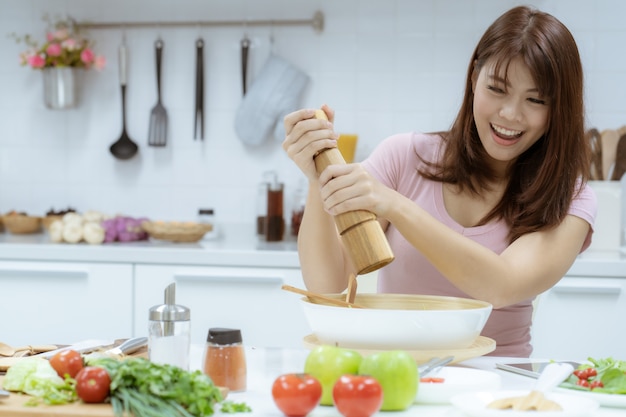 젊은 아름 다운 여자는 지방과 칼로리를 먹는 대신 샐러드와 과일을 먹음으로써 건강을 돌보아줍니다.