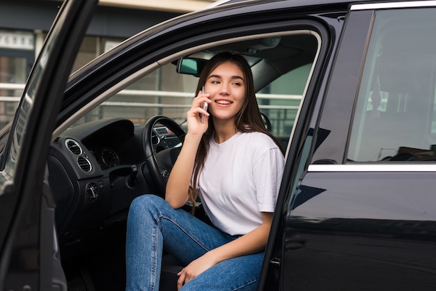 車に座って電話で話している若い美しい女性