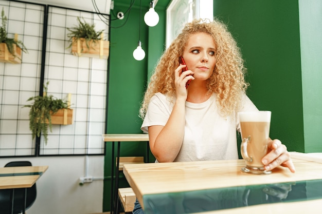 Молодая красивая женщина разговаривает по телефону в кафетерии крупным планом