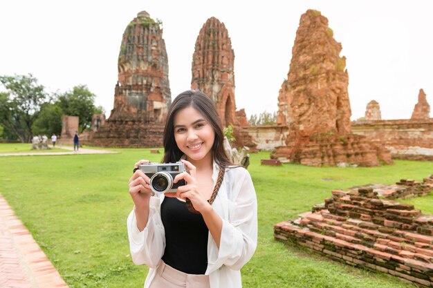 Молодая красивая женщина путешествует и фотографируется в тайском историческом парке