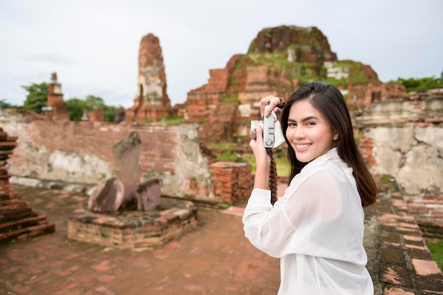 Young beautiful woman traveling and taking photo at thai historical Park