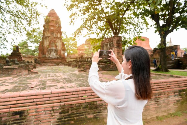 Young beautiful woman traveling and taking photo at thai historical Park