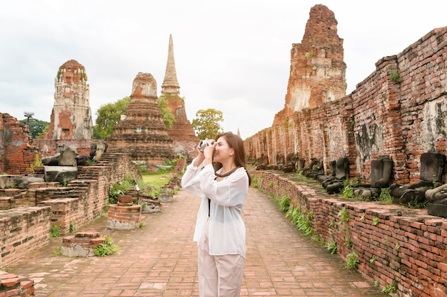 Young beautiful woman traveling and taking photo at thai historical Park