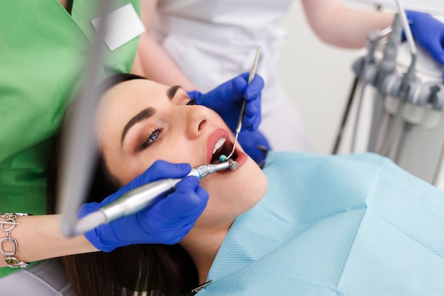 Young beautiful woman treats teeth at the dentist cabinet. Dental treatment process