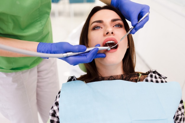 Young beautiful woman treats teeth at the dentist cabinet