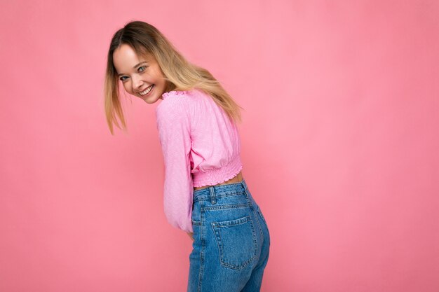 Young beautiful woman trendy woman in fashionable pink crop top positive female shows facial