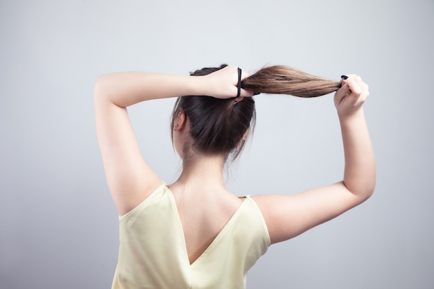 Foto giovane bella donna che lega i suoi capelli.