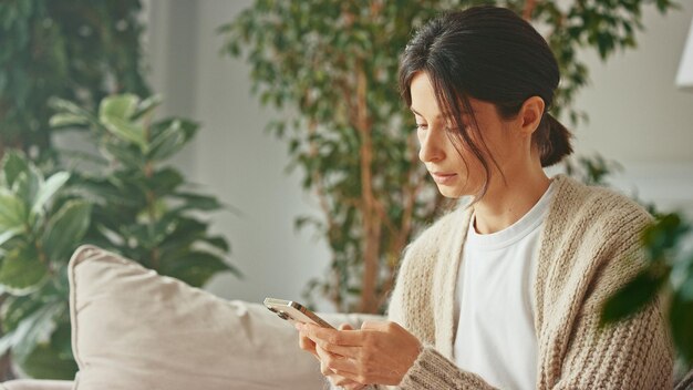 Young beautiful woman typing message using smartphone