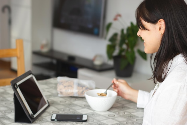 Foto giovane bella donna con tavoletta digitale durante una sana colazione