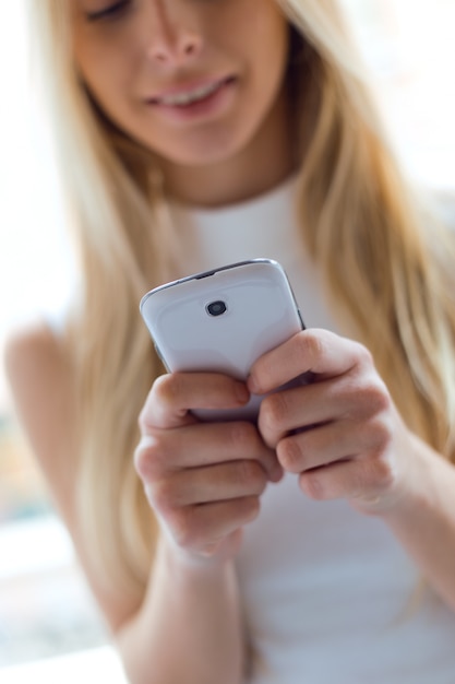 Young beautiful woman using her mobile phone at home.