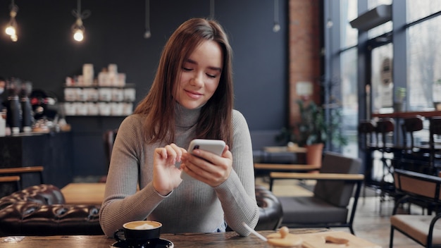 携帯電話アプリ、テキストメッセージメッセージを使用して若い美しい女性