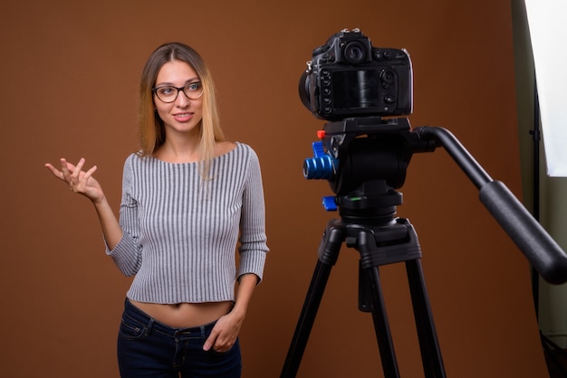Giovane bella donna vlogging con fotocamera dslr in studio