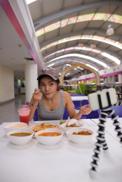 Young beautiful woman vlogging with mobile phone in restaurant