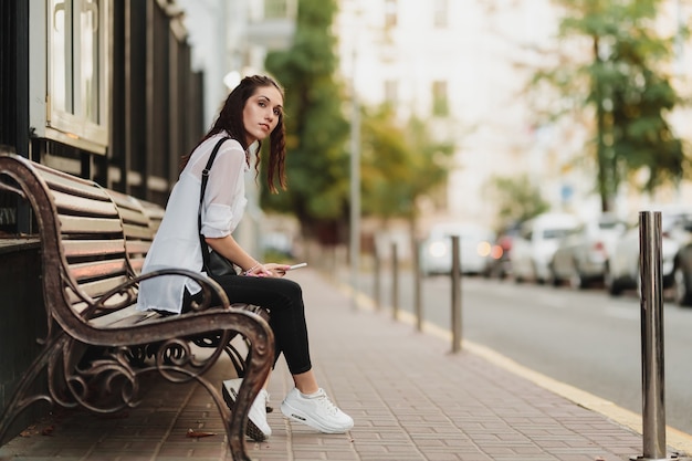 Young beautiful woman waiting for the bus at the stop. High quality photo