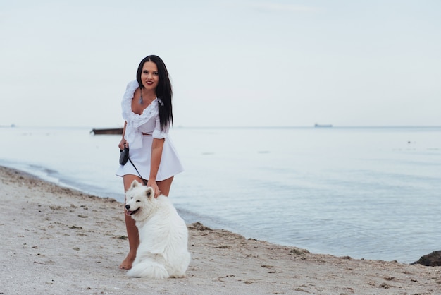 Young beautiful woman walking with her dog on the beach