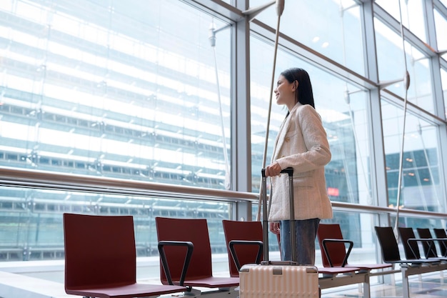 Una giovane bella donna che cammina con la valigia fa il check-in all'aeroporto internazionale