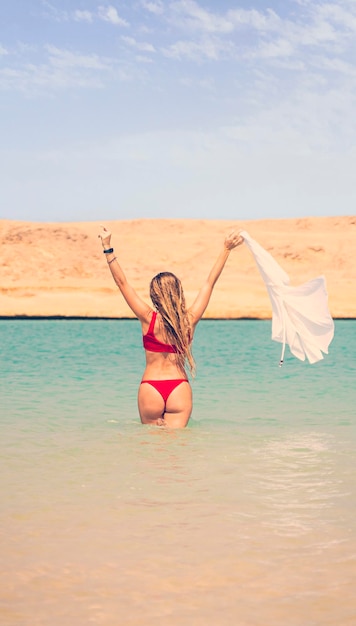 Young beautiful woman walks on the turquoise water of the red sea Sharm el Sheikh Egypt The concept of a summer holiday by the sea