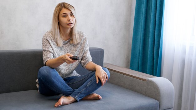 Young beautiful woman watching television on couch at living room 