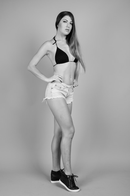 young beautiful woman wearing bikini against gray wall in black and white