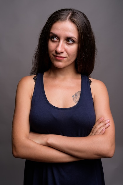 young beautiful woman wearing blue sleeveless dress on gray