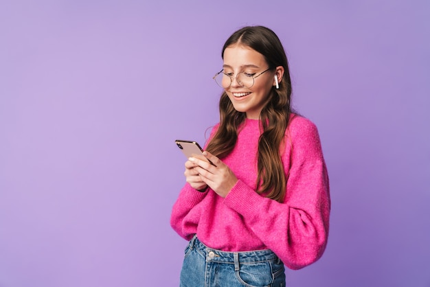 young beautiful woman wearing earbuds smiling and holding cellphone isolated