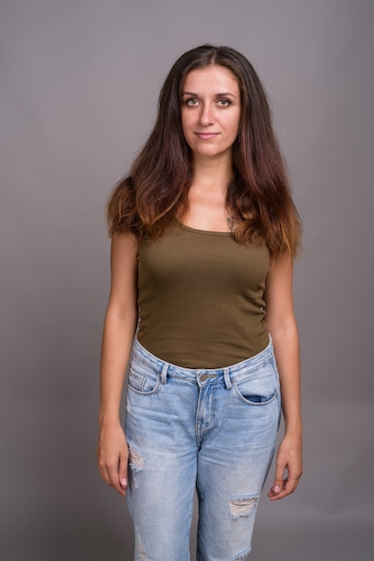 young beautiful woman wearing green sleeveless top on gray