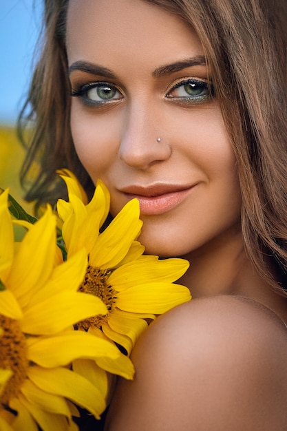 Young beautiful woman wearing a hat in a field of sunflowers