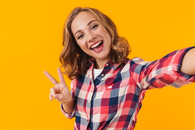young beautiful woman wearing plaid shirt smiling and taking selfie isolated
