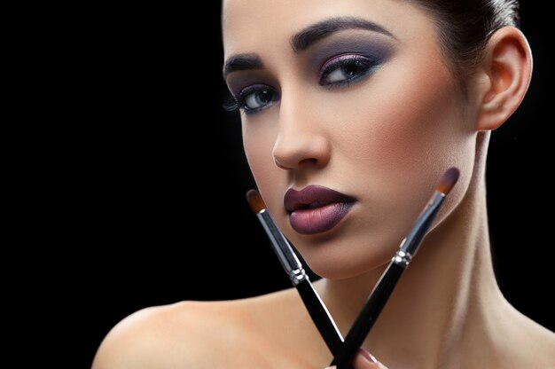 Young beautiful woman wearing professional makeup holding makeup