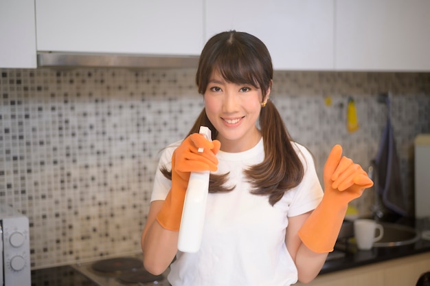 Photo a young beautiful woman wearing protective rubber gloves is cleaning table in kitchen at home.