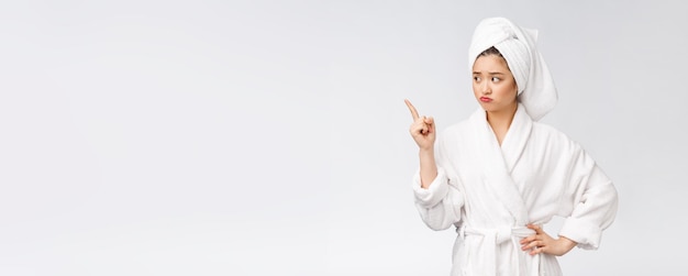 Young beautiful woman wearing shower towel after bath over isolated white background pointing with finger