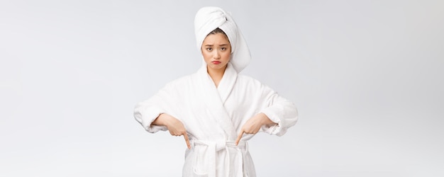 Young beautiful woman wearing shower towel after bath over isolated white background pointing with finger