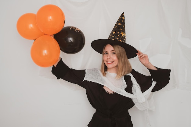 Young beautiful woman wearing witch hat halloween costume on white background