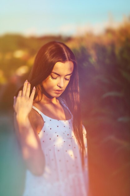 Photo young beautiful woman in white dress in corn field surreal blurry portrait