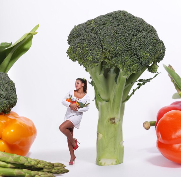 Young beautiful woman in white dress wit h fresh vegetables