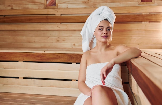 Young beautiful woman in white towel have a rest in the sauna Conception of bodycare