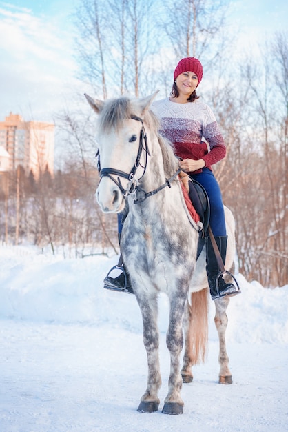 Giovane bella donna in inverno con bellissimo cavallo bianco