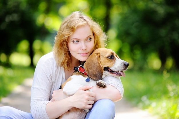 夏の公園でビーグル犬を持つ若い美しい女性。彼女の国内ペットとの愛情のある女性の所有者