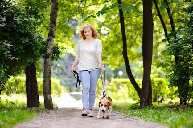 Фото Молодая красивая женщина с бигл собака в парке летом. любящая женщина-хозяин со своим домашним питомцем