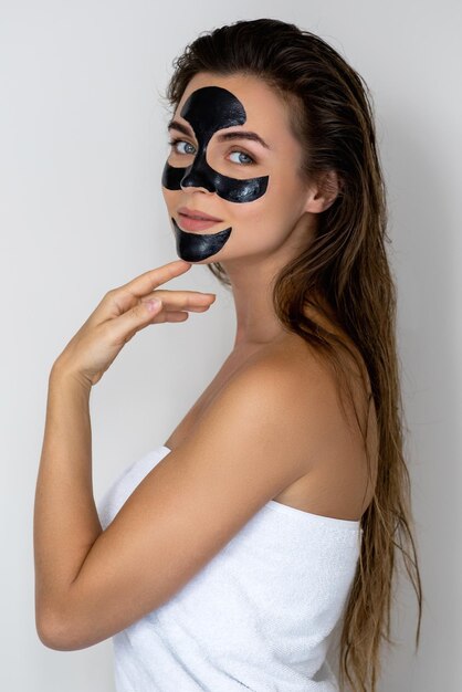 Photo young and beautiful woman with black peel-off mask on her face