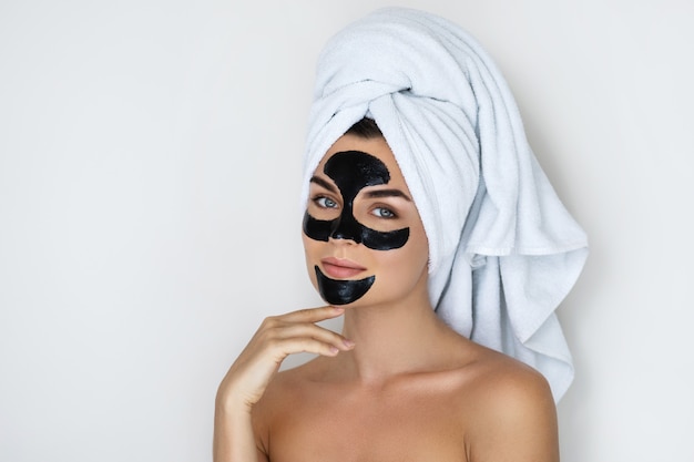 Young and beautiful woman with black peel-off mask on her face