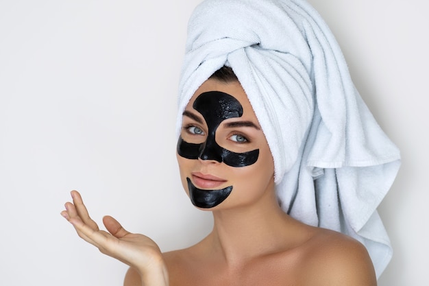 Young and beautiful woman with black peel-off mask on her face