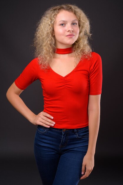 Young beautiful woman with blond curly hair against gray