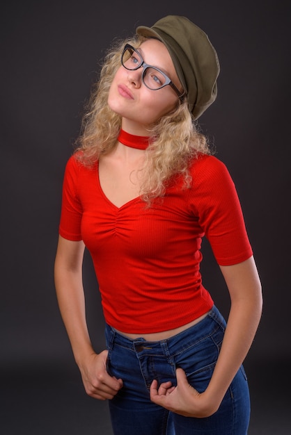 Young beautiful woman with blond curly hair against gray